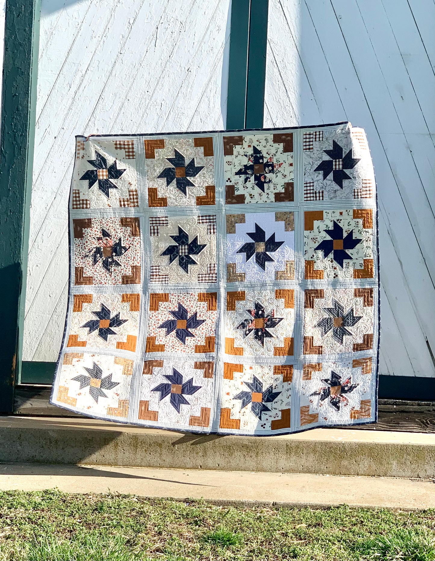 Handcrafted quilt featuring star patterns in navy, brown, and cream colors, perfect for home decor.