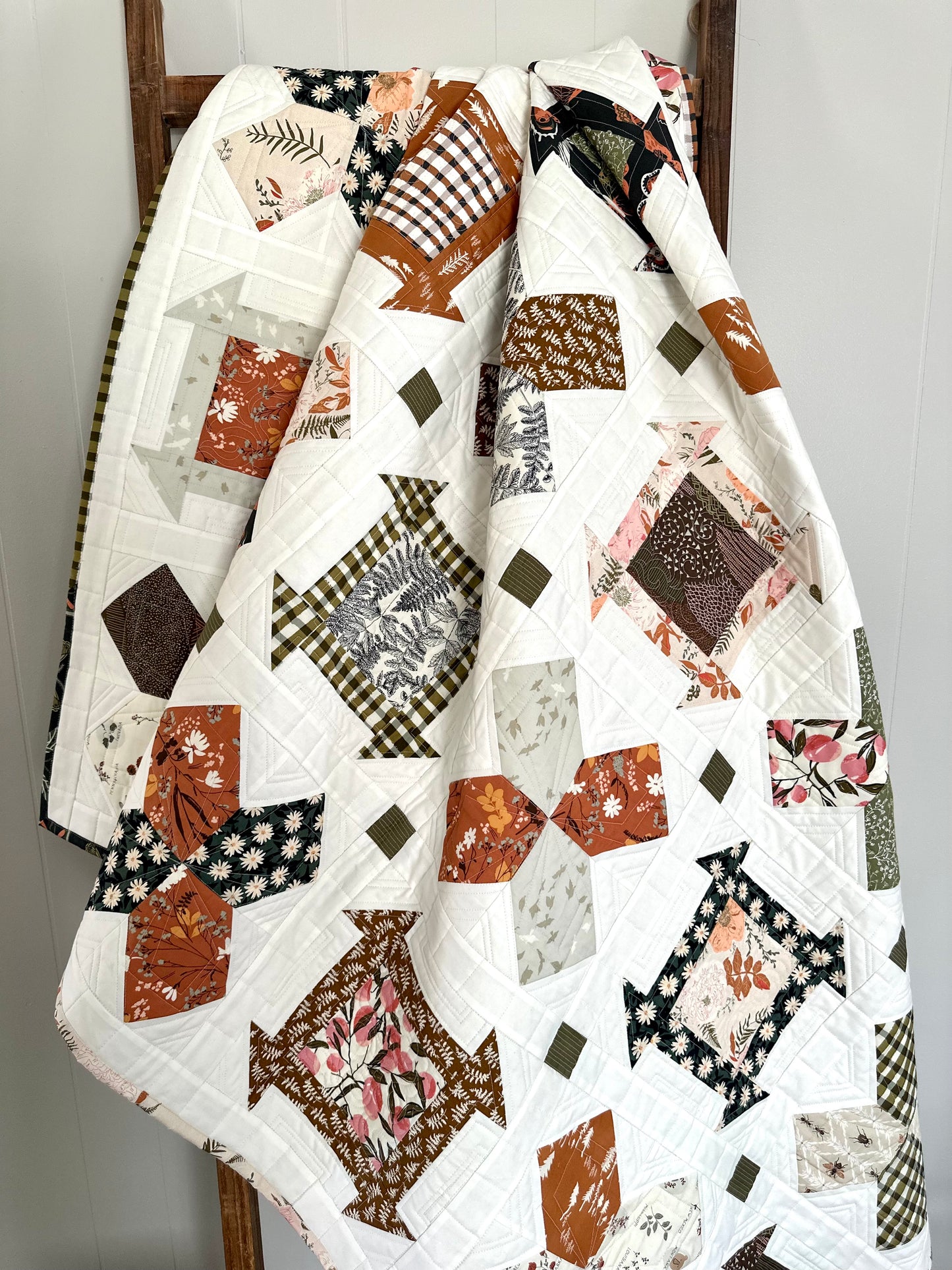 Colorful quilt featuring floral and geometric patterns in warm tones and white, perfect for home decor.