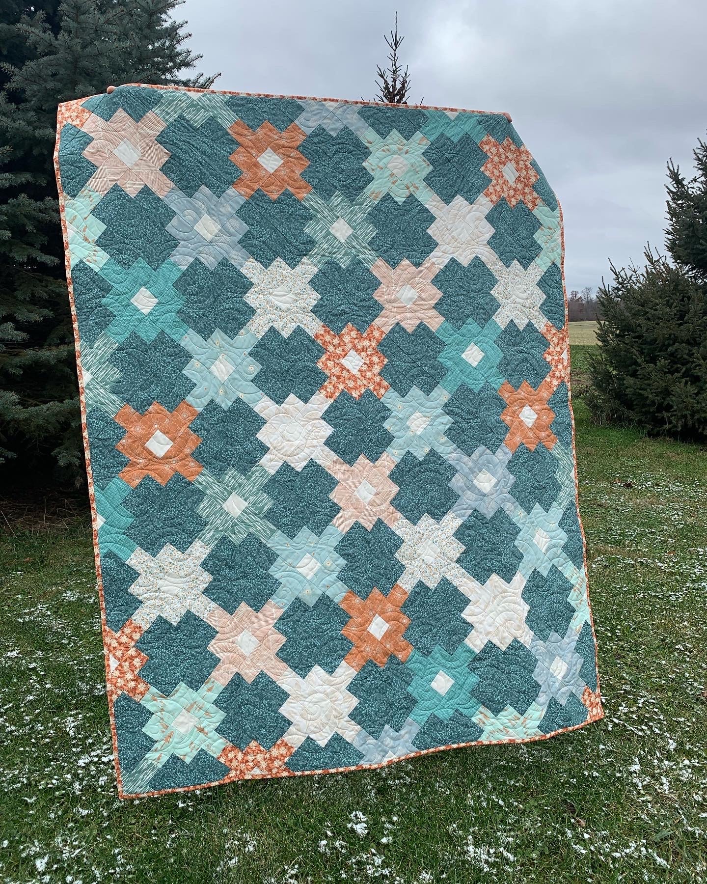 Handmade teal, coral, and cream quilt with floral pattern, perfect for home decor or cozy warmth.
