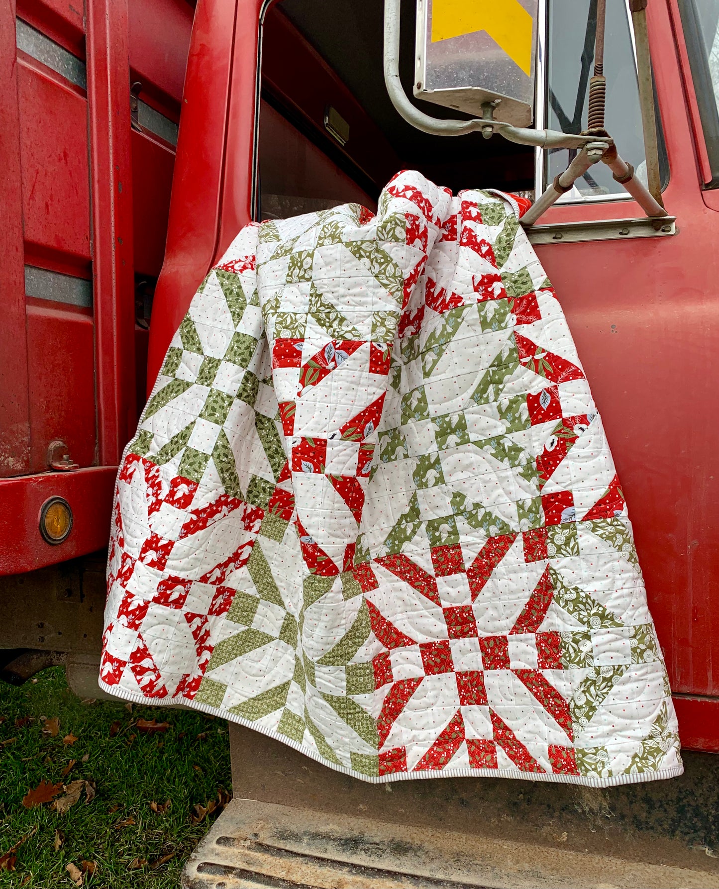Colorful quilt with red, green, and white patterns, perfect for cozy decor and seasonal warmth.