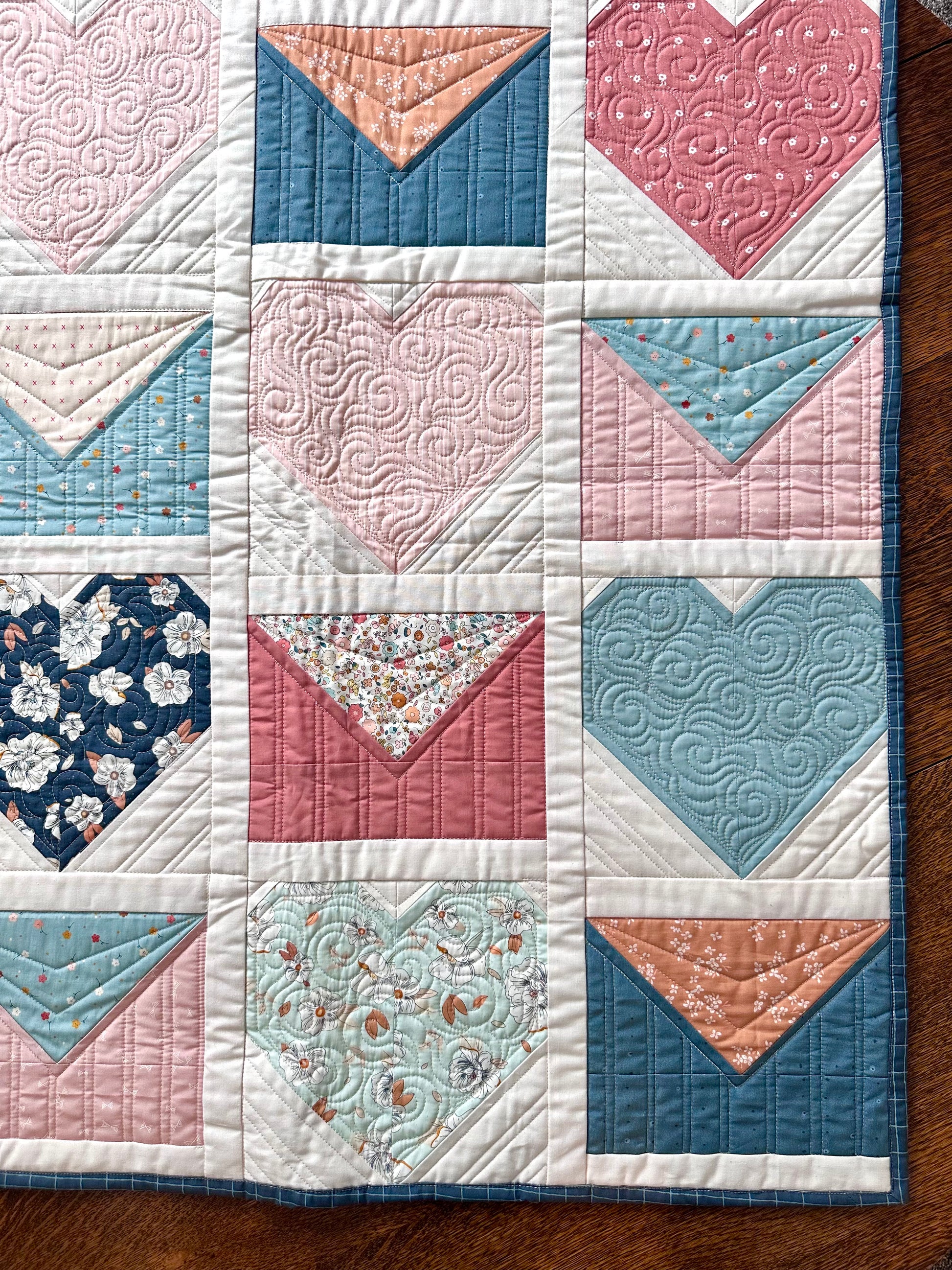 Colorful heart-patterned quilt with floral and geometric designs, featuring soft cotton material.