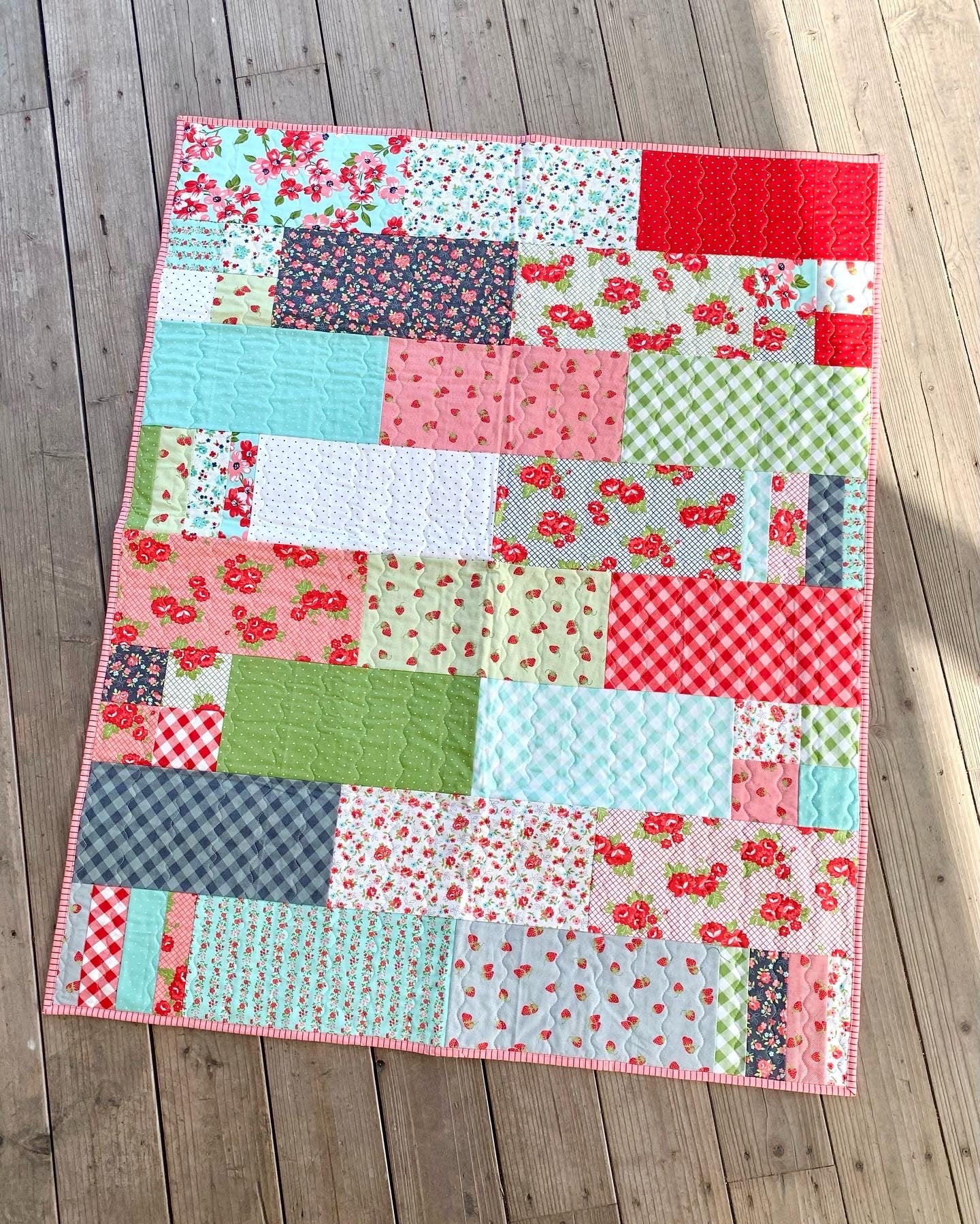 Colorful patchwork quilt featuring floral patterns in pink, green, and blue, perfect for home decor.