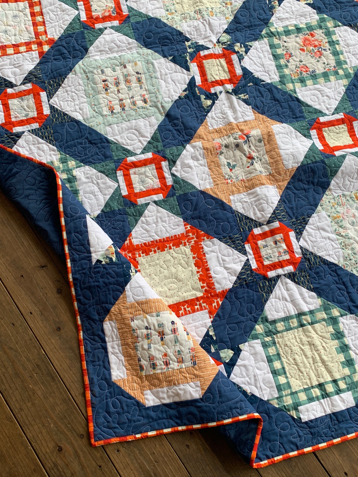 Colorful quilt featuring geometric patterns, navy blue, orange, and green accents, made from high-quality fabric.