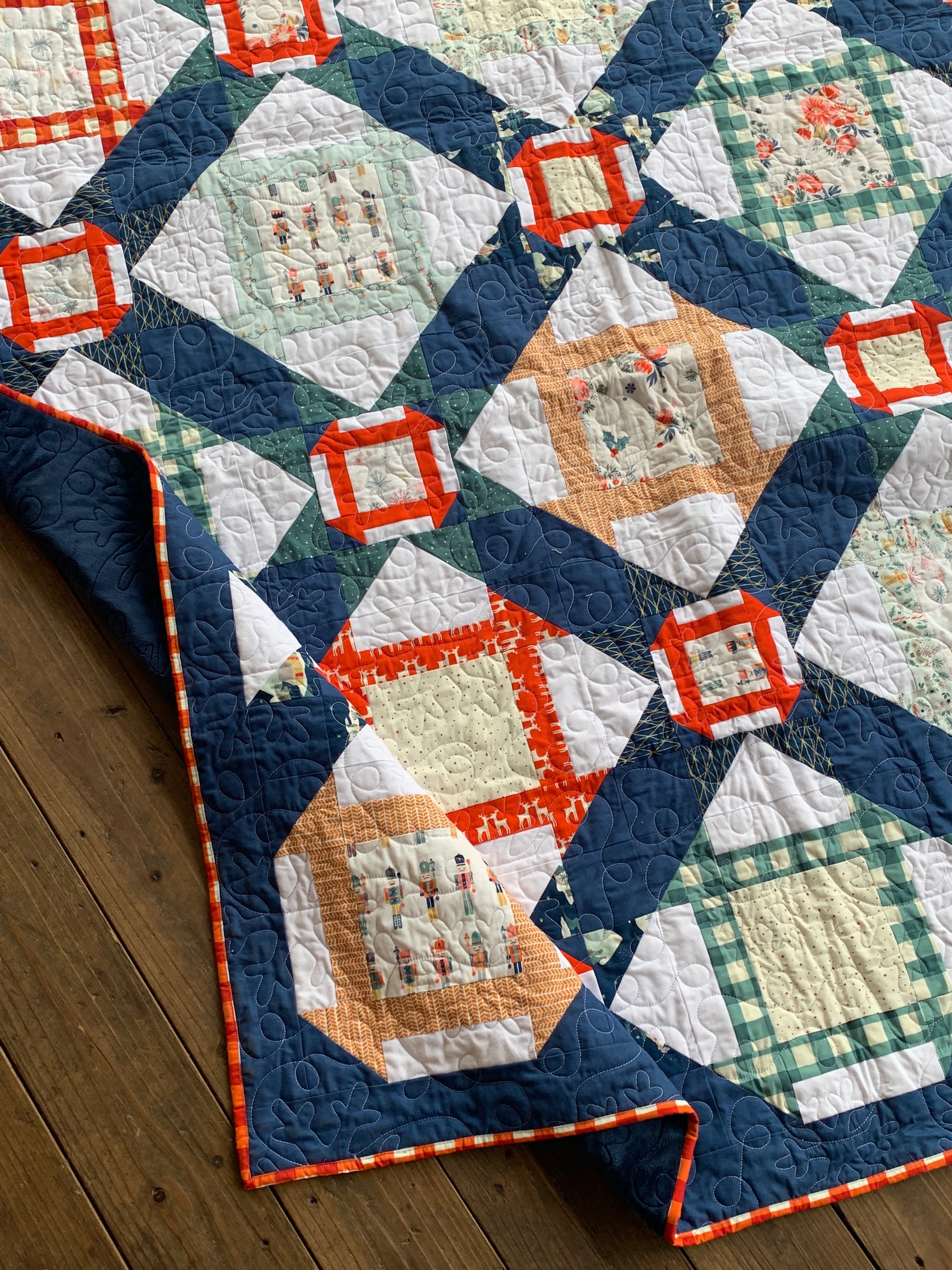 Colorful quilt featuring geometric patterns, navy blue, orange, and green accents, made from high-quality fabric.