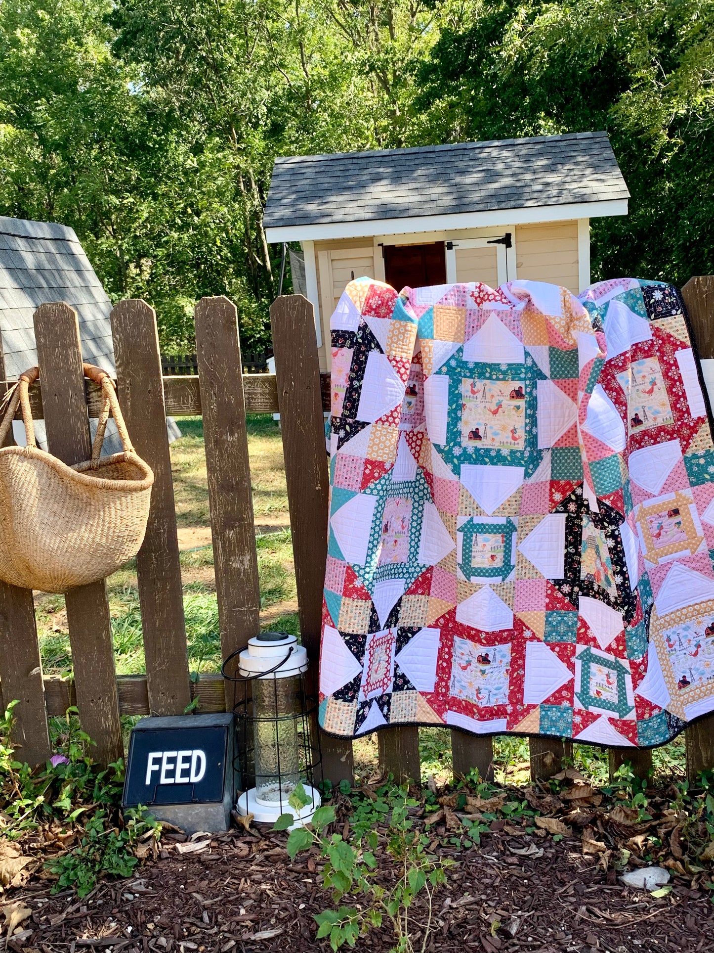 Colorful patchwork quilt hanging on a wooden fence, featuring various patterns and cozy fabric textures.