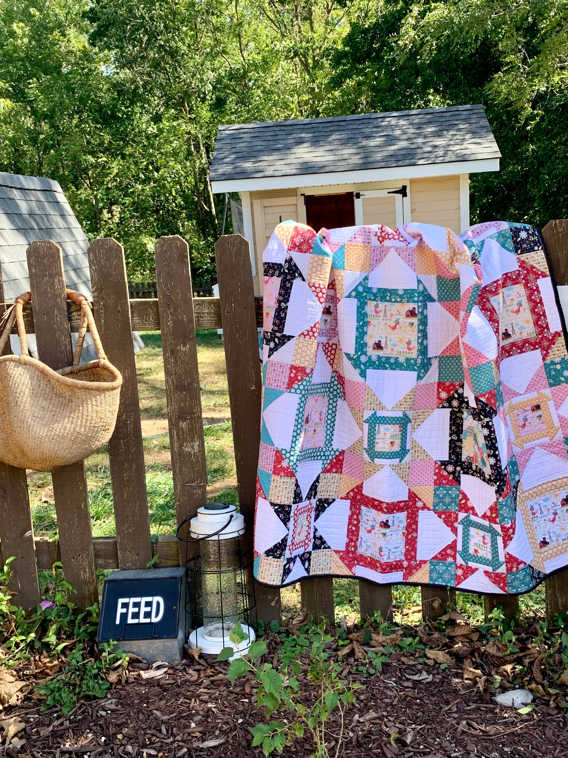Colorful patchwork quilt hanging on a wooden fence, featuring various patterns and cozy fabric textures.