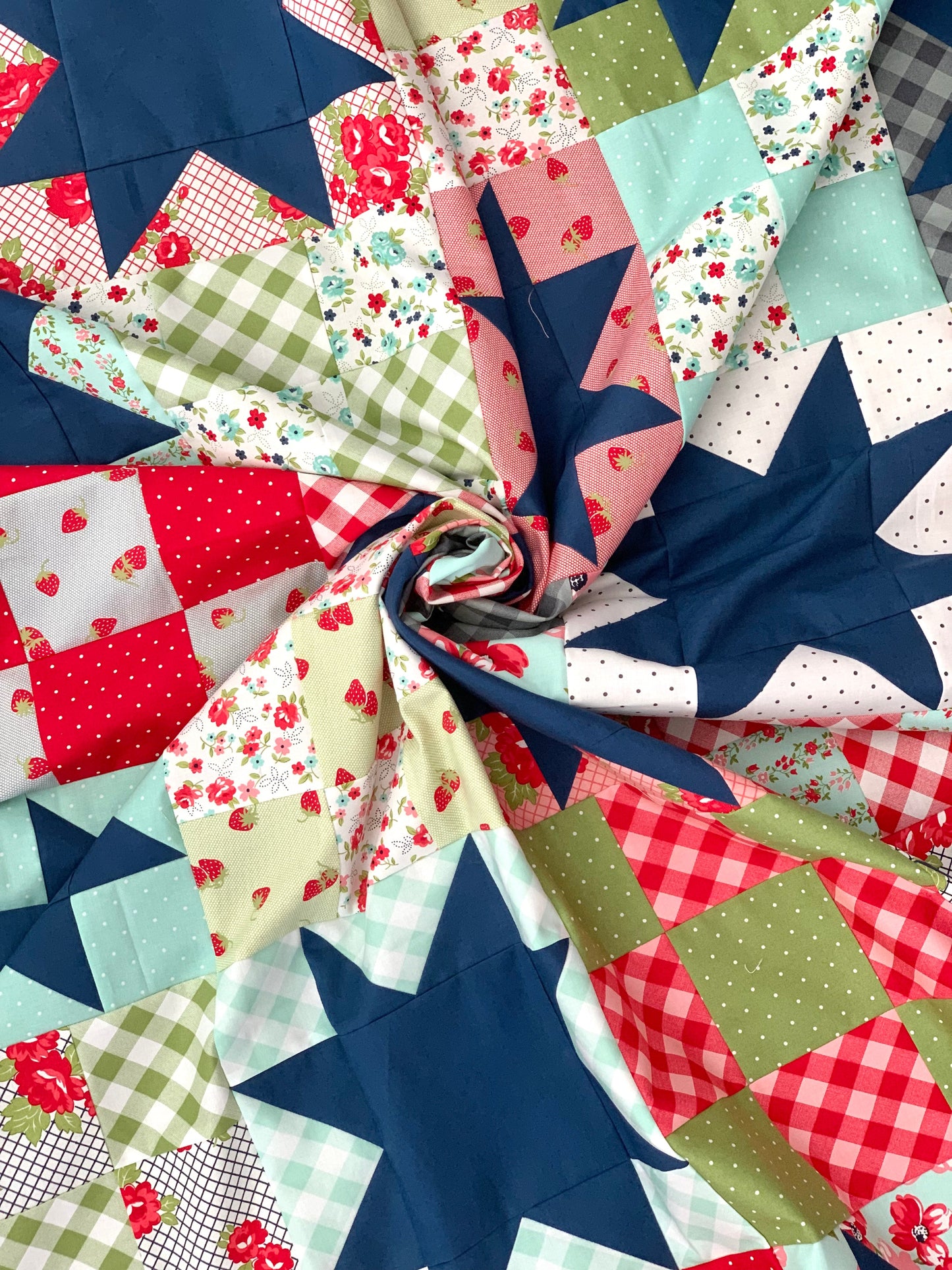 Colorful quilt fabric featuring floral and star patterns in red, blue, green, and pastel colors.