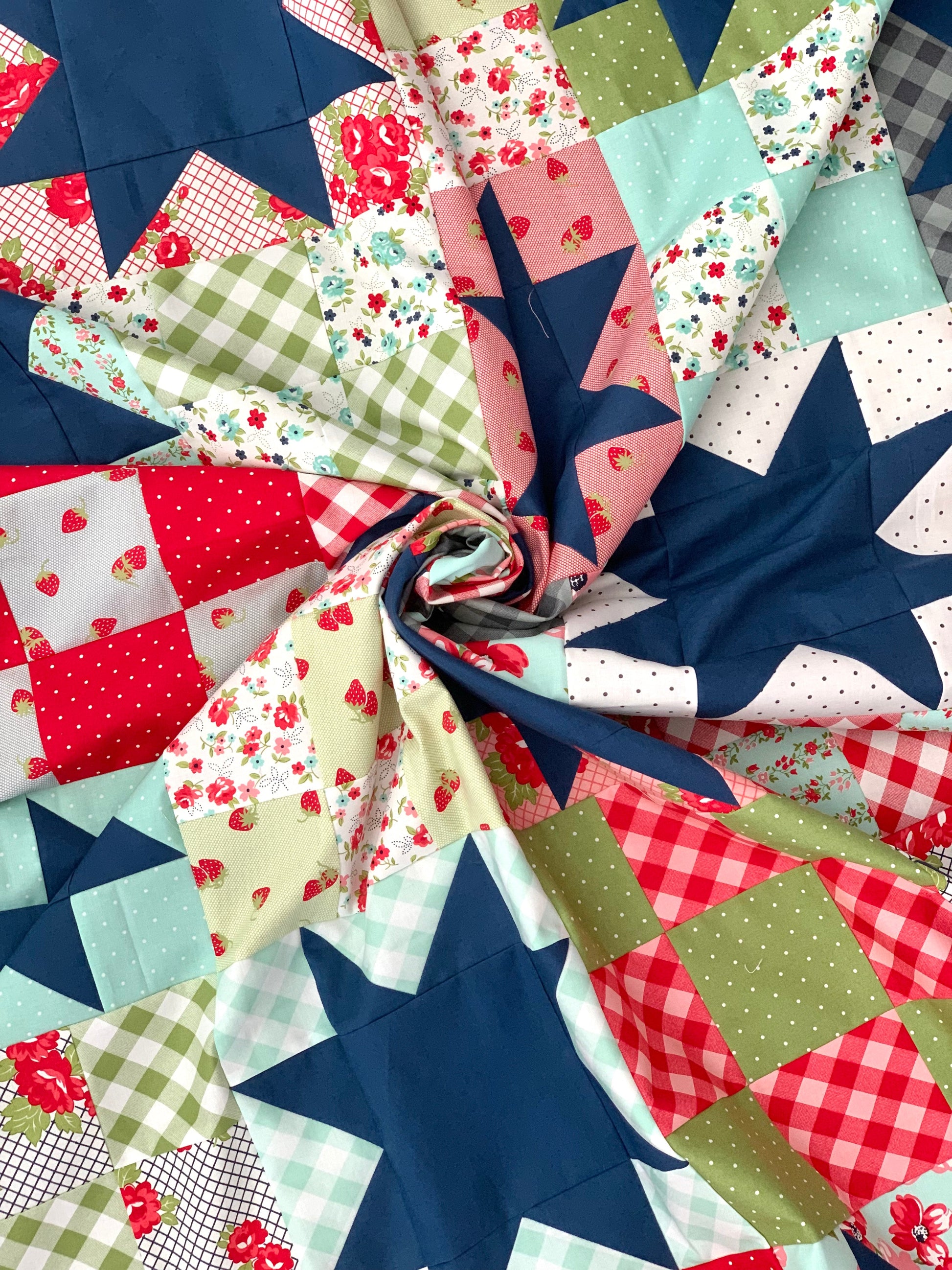 Colorful quilt fabric featuring floral and star patterns in red, blue, green, and pastel colors.