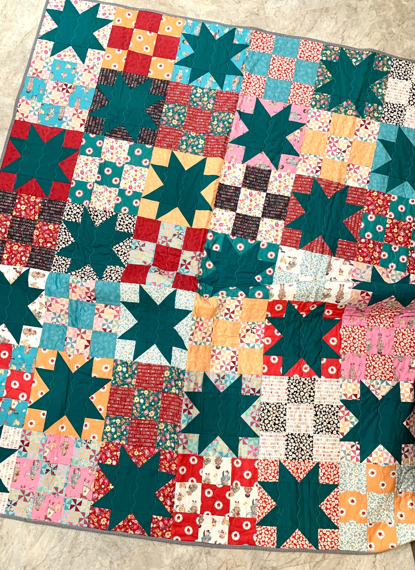 Colorful patchwork quilt featuring teal stars, floral patterns, and vibrant squares, perfect for cozy decor.