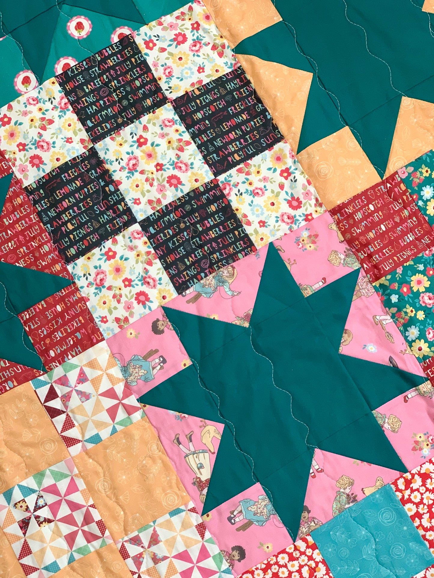 Colorful patchwork quilt in teal, pink, and floral patterns, made from cotton fabric.