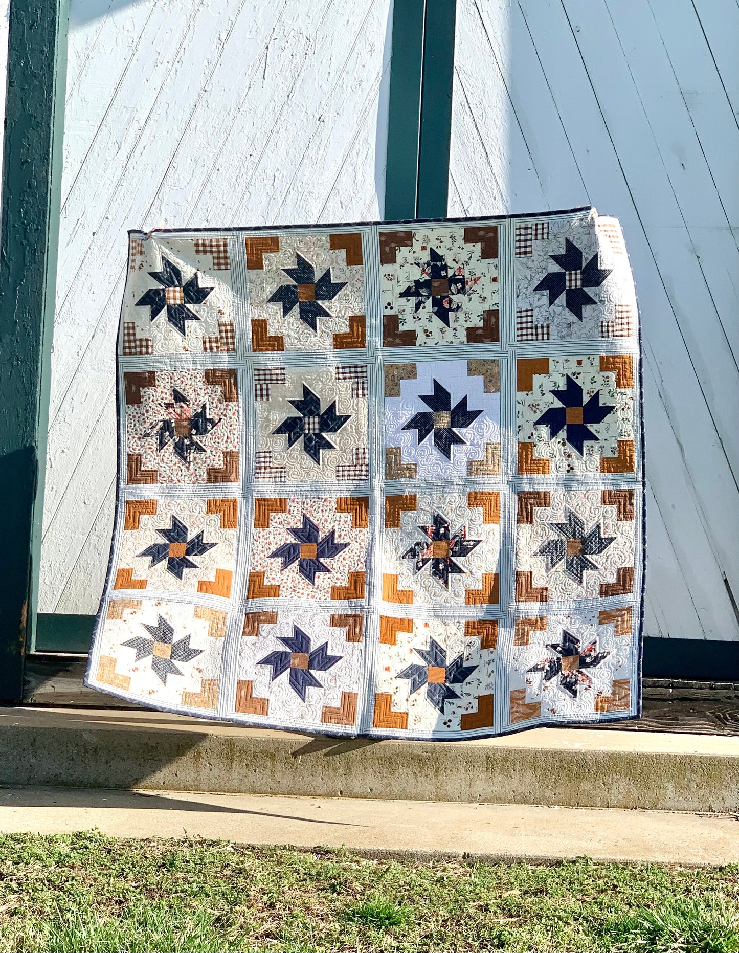 Handmade quilt featuring star patterns in navy, brown, and cream colors, perfect for home decor.