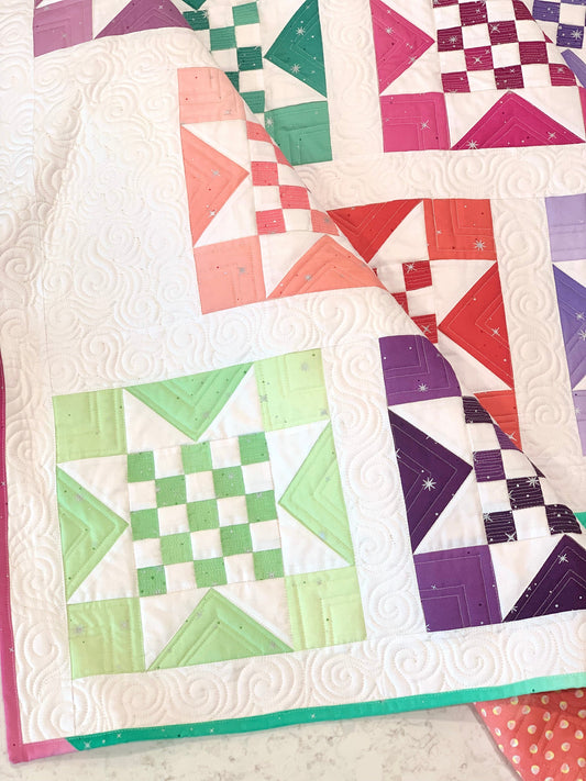 Colorful quilt featuring geometric patterns in peach, green, purple, and white, crafted from premium fabric.