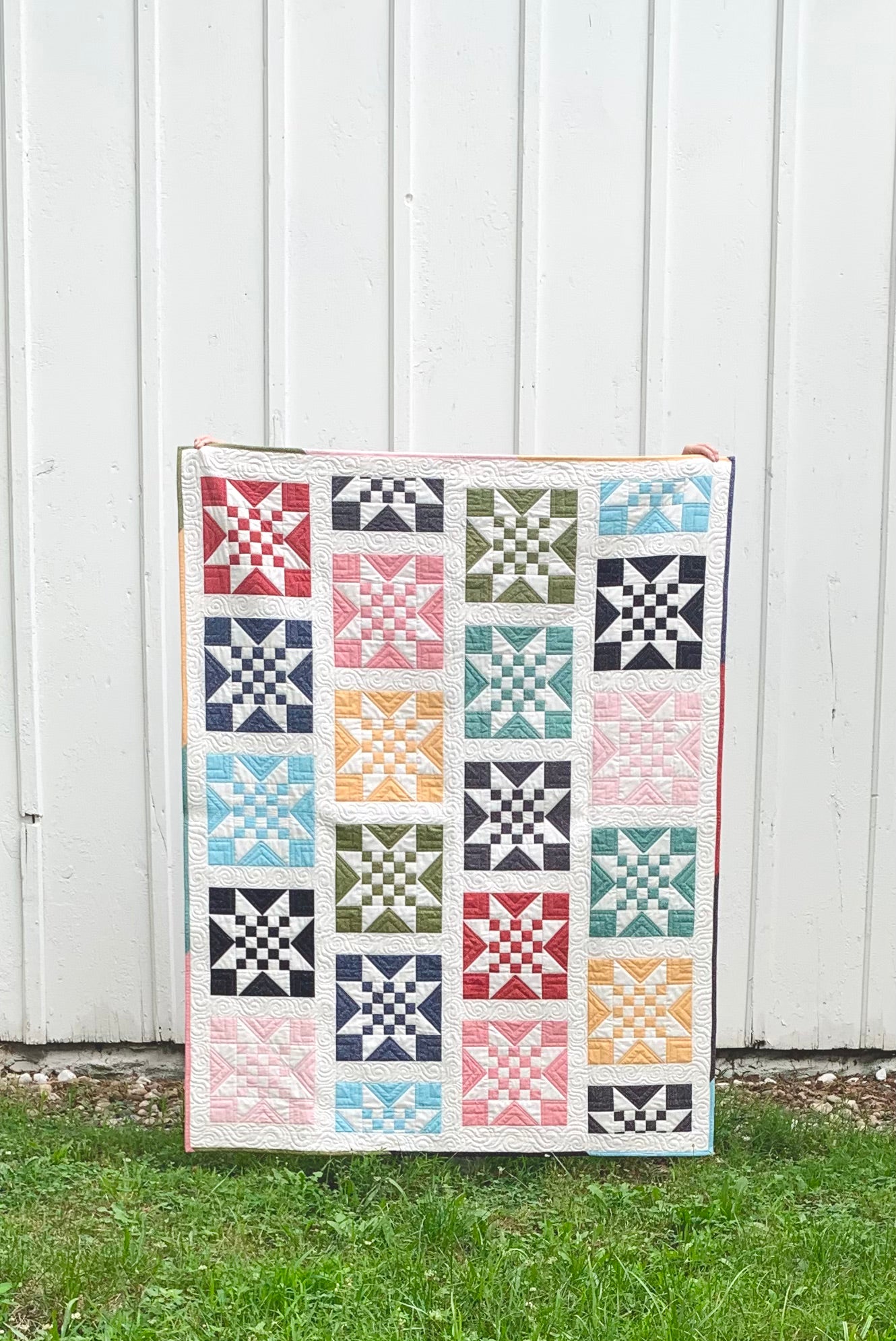 Colorful quilt featuring star patterns in red, blue, green, and pink, crafted from high-quality fabric.