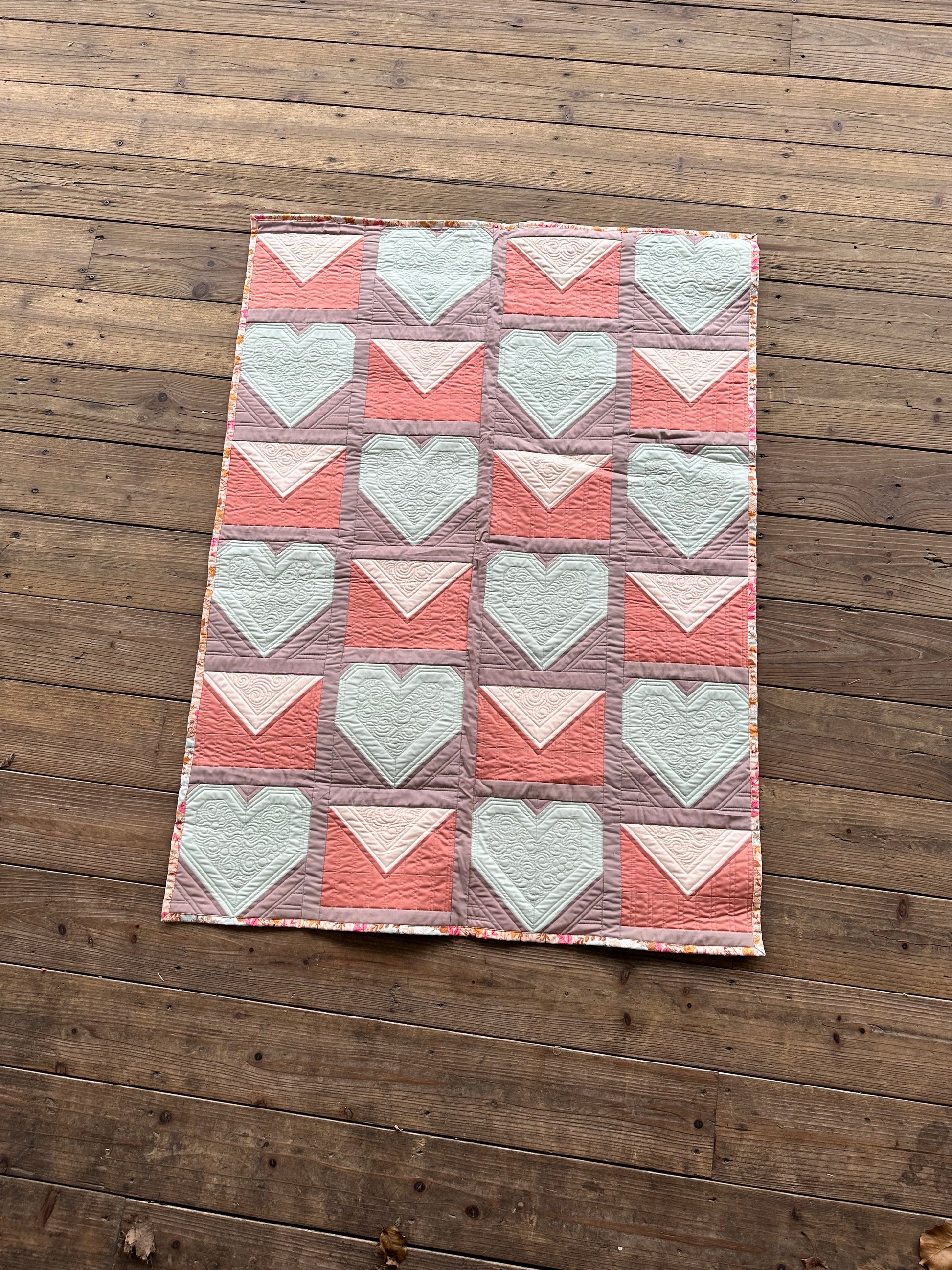 Colorful heart-pattern quilt in pink and mint, made from soft cotton, perfect for cozy home decor.