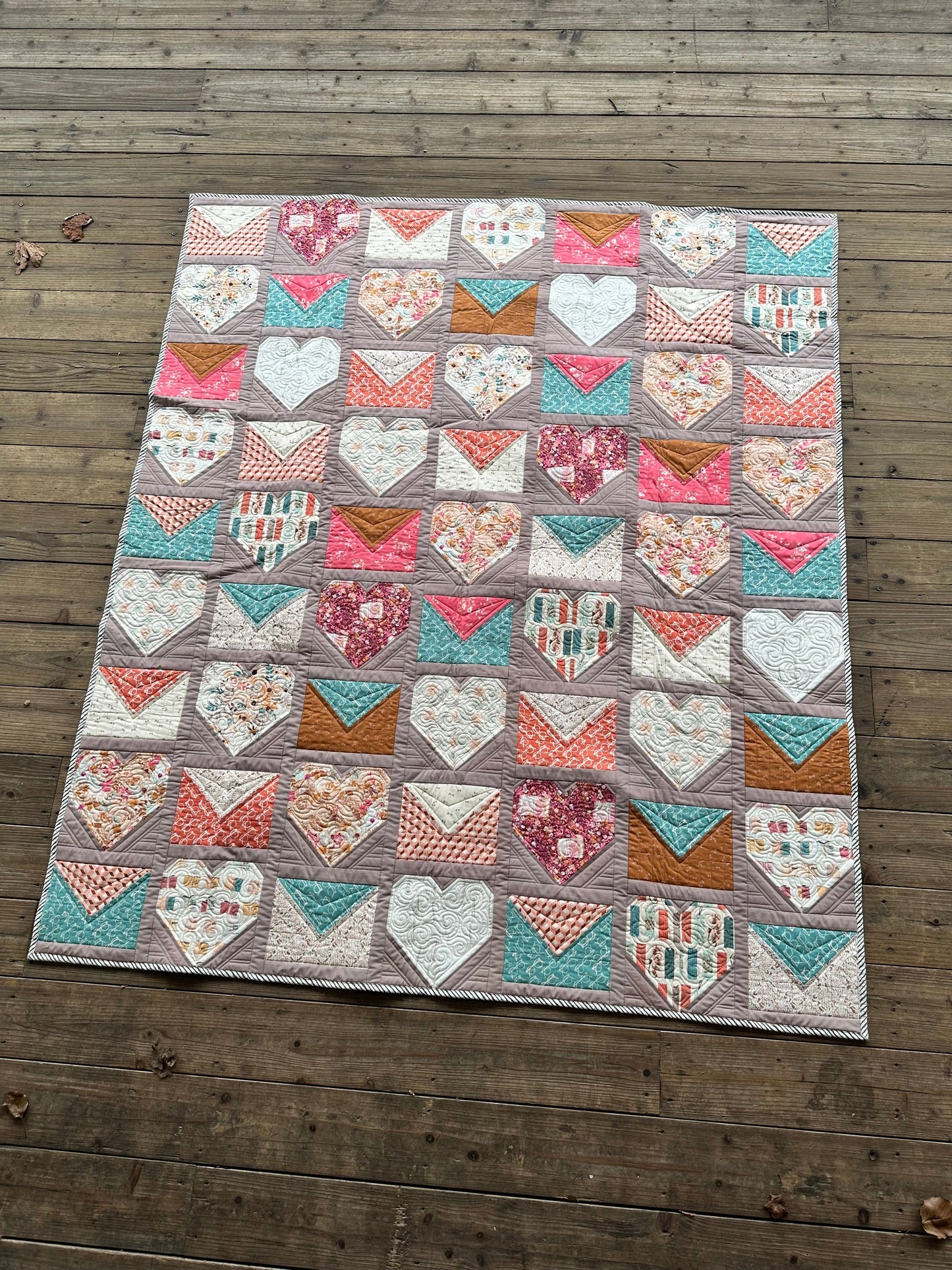 Colorful heart quilt in pink, teal, and floral patterns, perfect for home decor and cozy blankets.