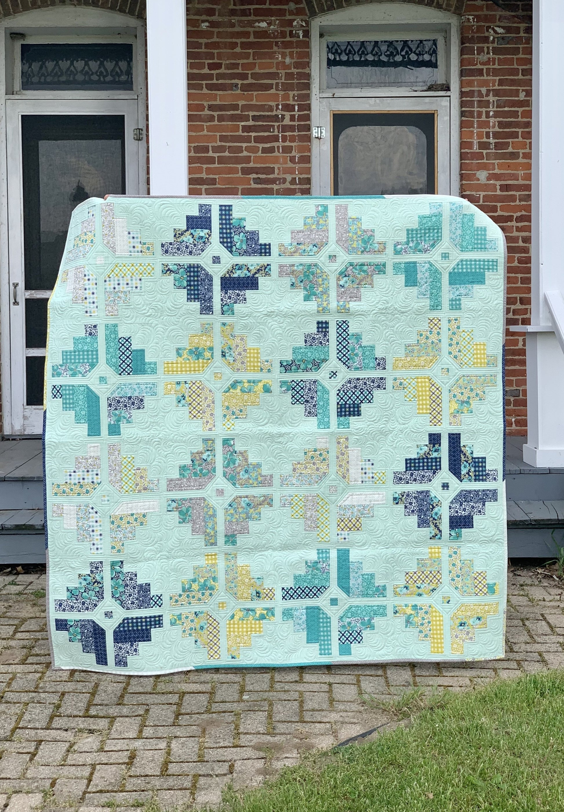 Colorful patchwork quilt in mint green, featuring floral and geometric patterns, ideal for cozy home decor.