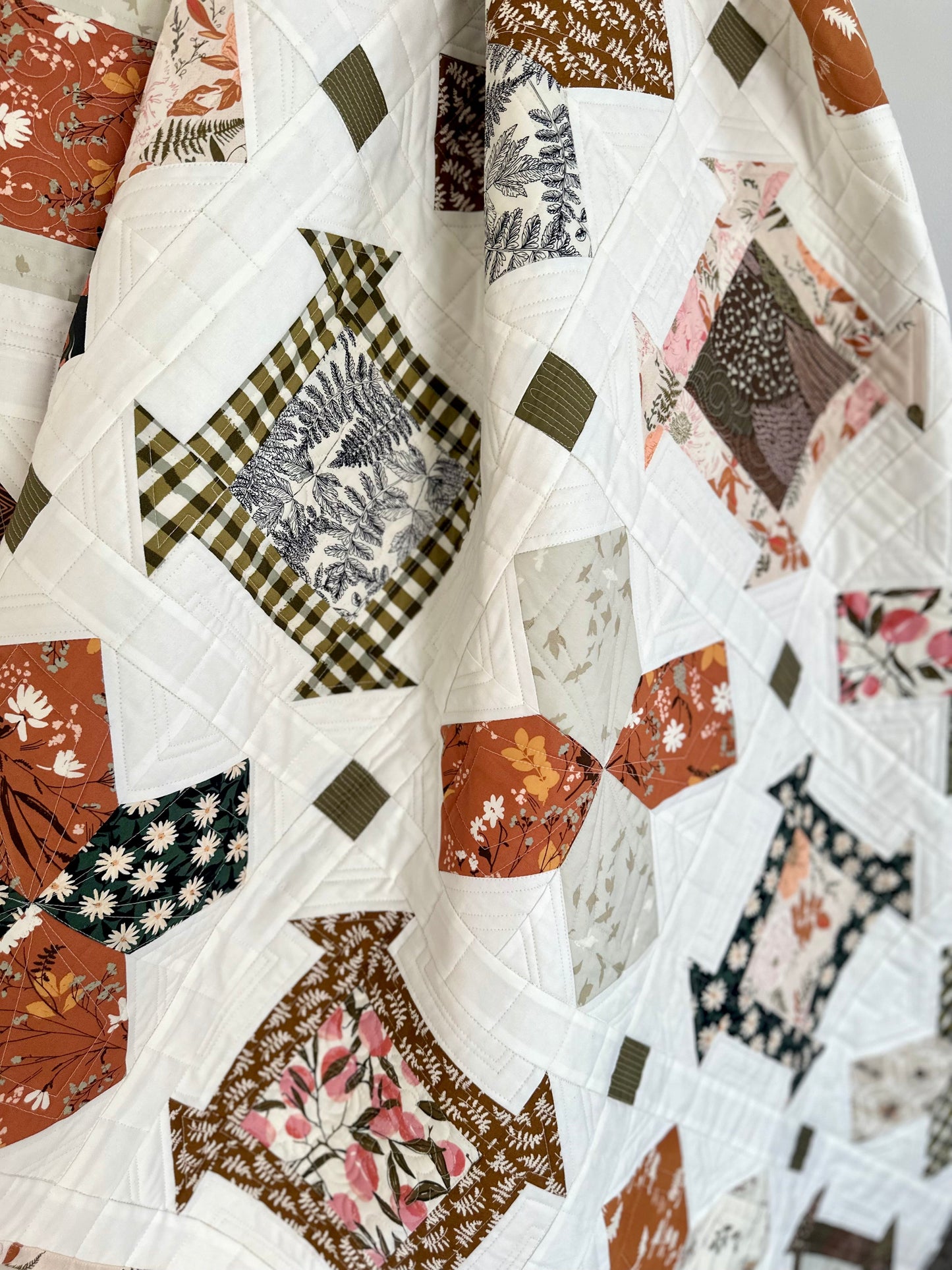 Colorful quilt featuring floral patterns in earthy tones, crafted from soft cotton fabric.