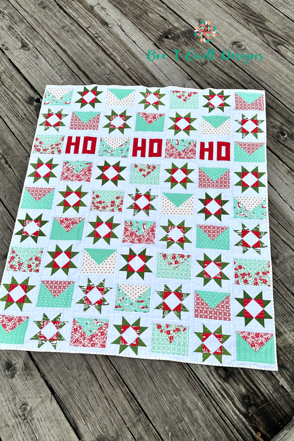 Colorful holiday quilt with red, green, and aqua patterns, featuring star designs and HO lettering.