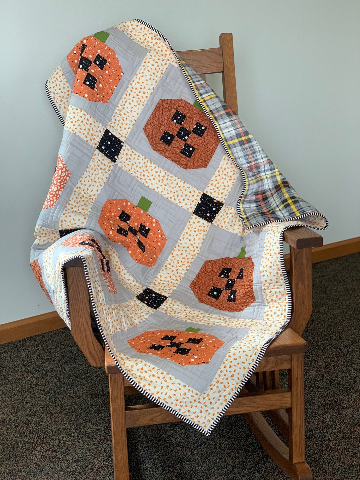 Cozy pumpkin quilt in orange and gray, featuring playful patterns, perfect for fall decor.