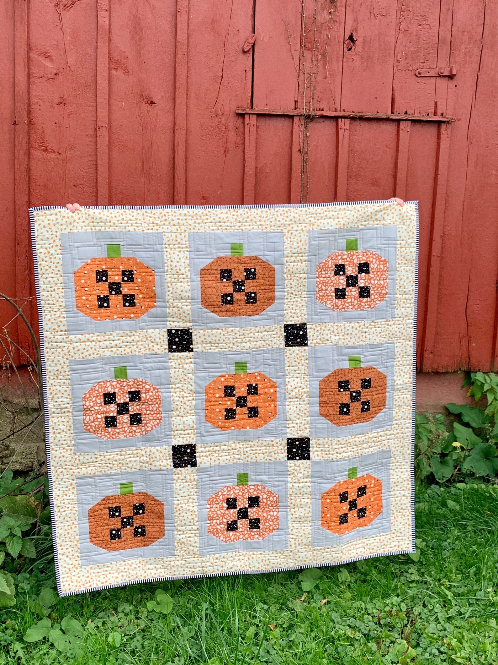 Handmade pumpkin quilt with orange and black fabric, perfect for fall decor, featuring patchwork design.