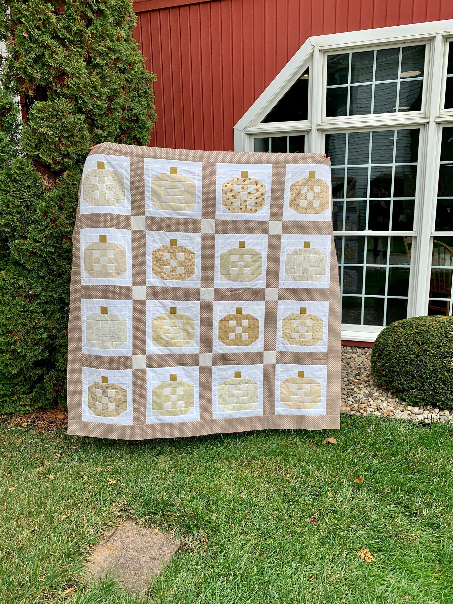 Handmade pumpkin quilt in neutral colors, perfect for autumn decor, featuring a patchwork design.