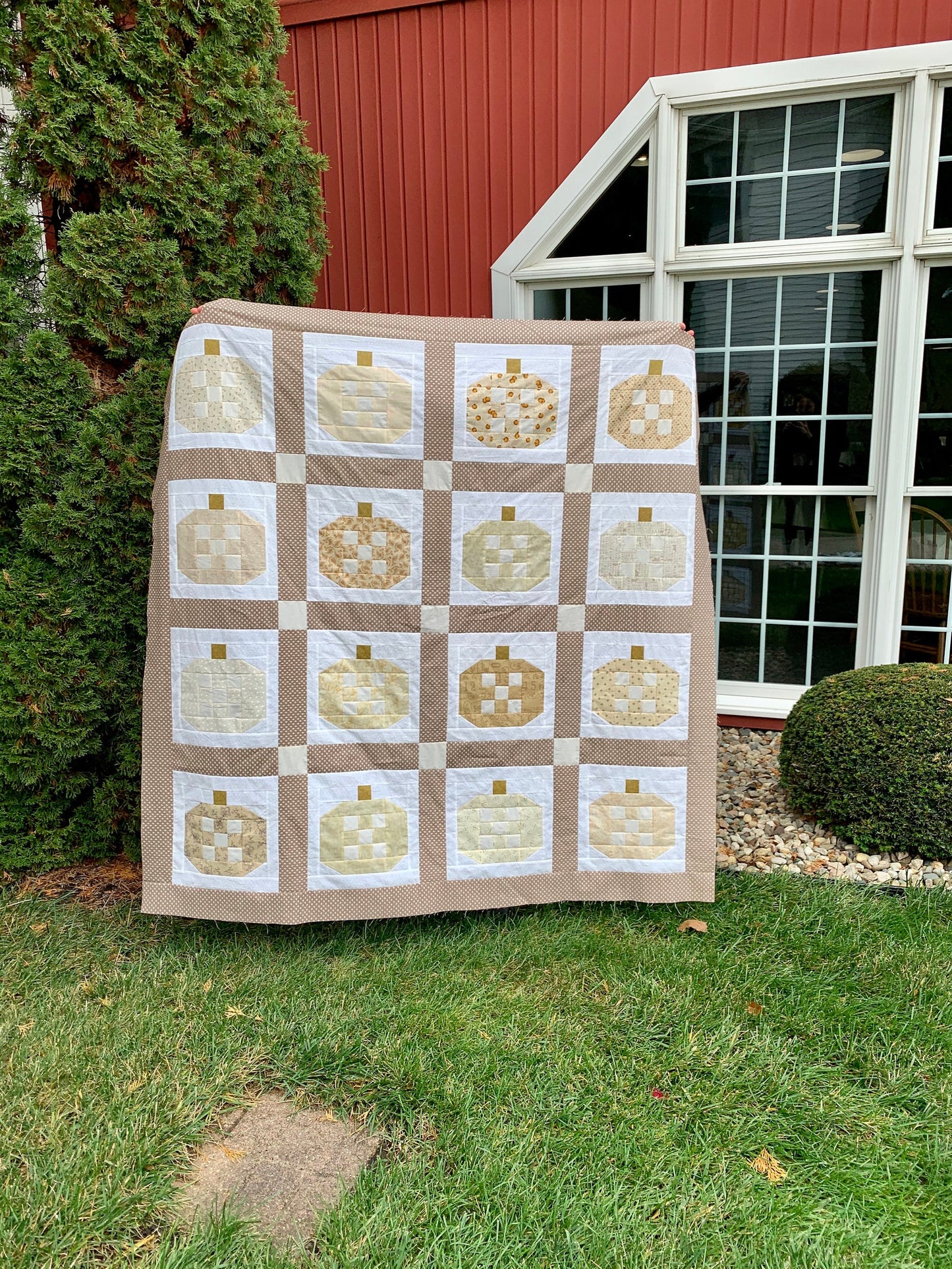 Cozy quilt featuring a pumpkin patch design in beige and white, perfect for autumn decor.