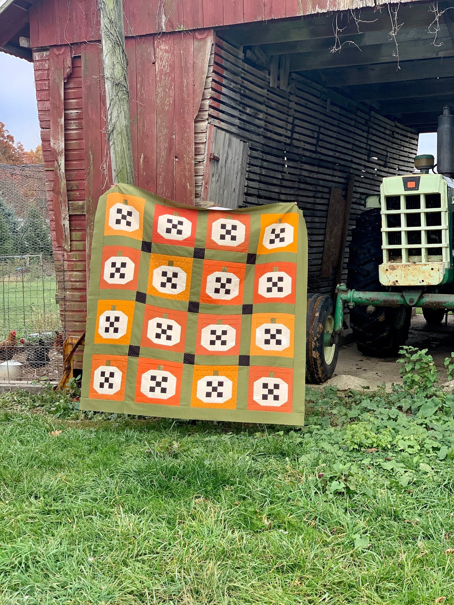 Colorful pumpkin quilt in orange, green, and yellow on a rustic barn backdrop.