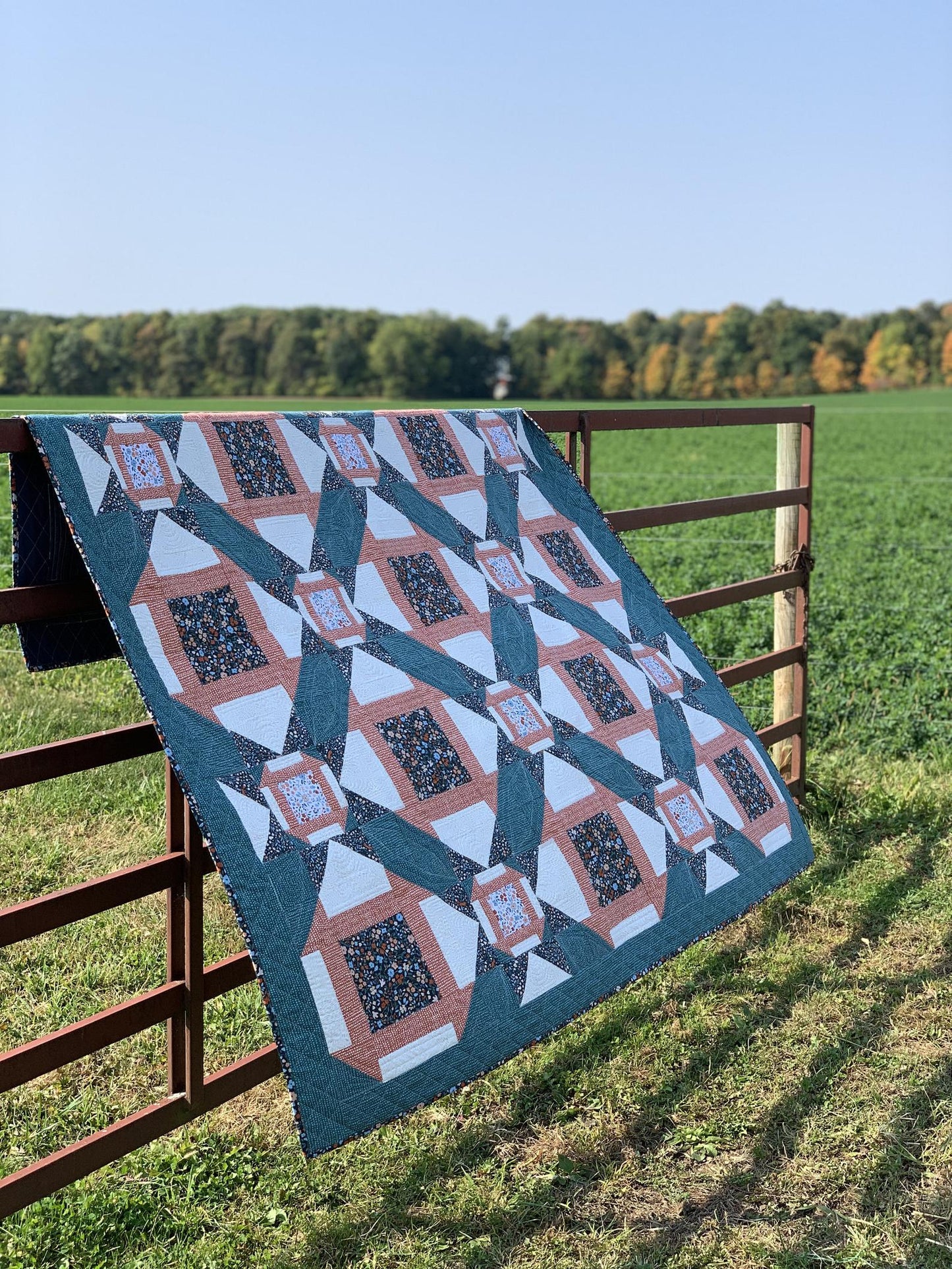 Handmade quilt in teal, orange, and white patterns, ideal for home decor or cozy evenings.