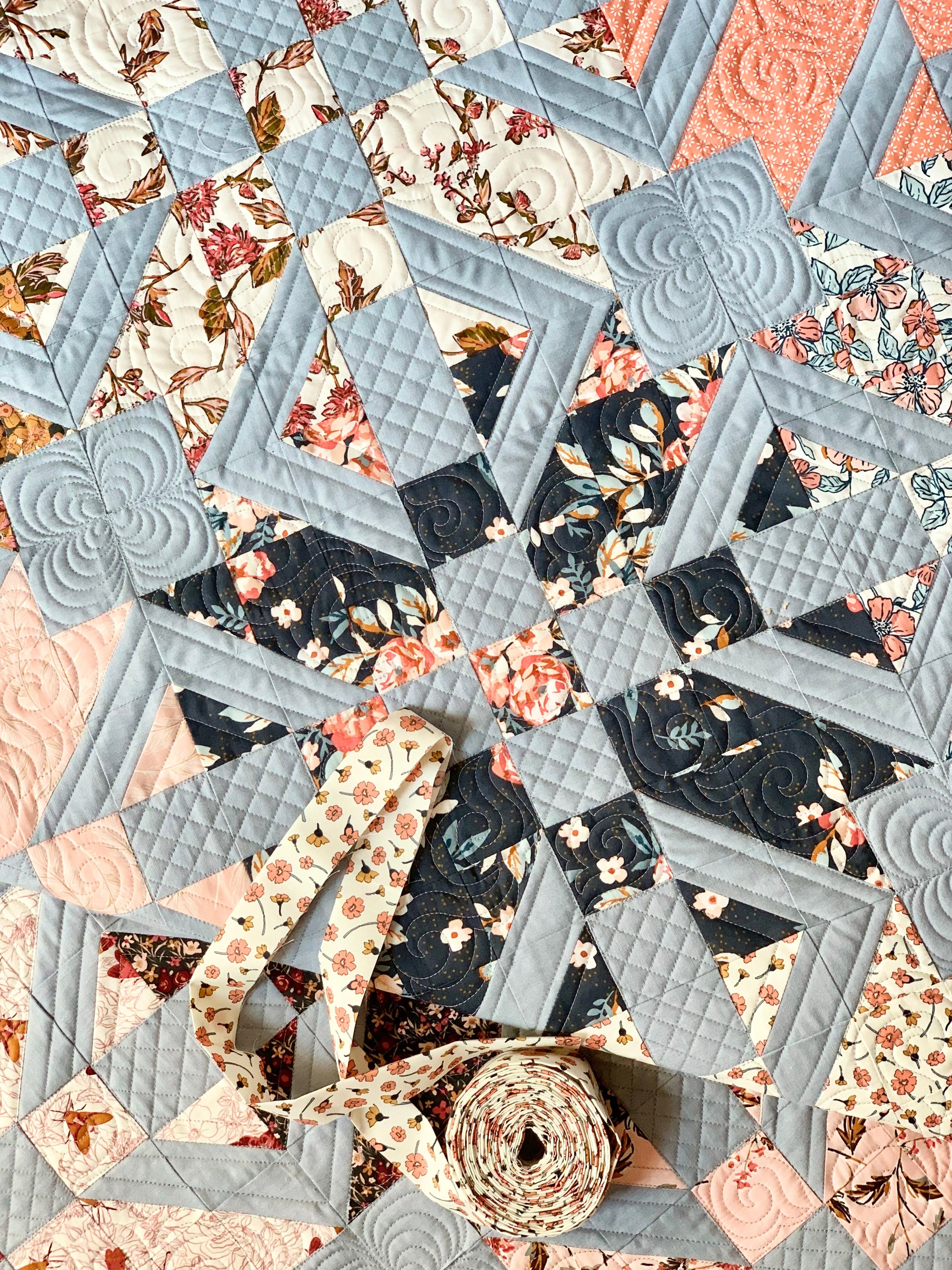 Beautifully quilted star pattern in pastel blue, floral prints, featuring pink and navy fabrics, perfect for decor.